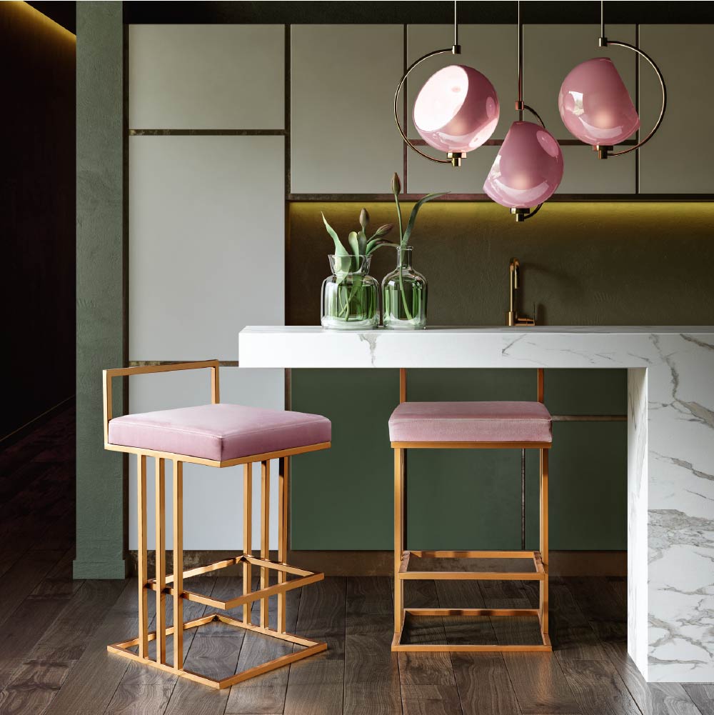 Dinette featuring pink upholstered stools with angular gold bases, round pendant lights and white marble counter